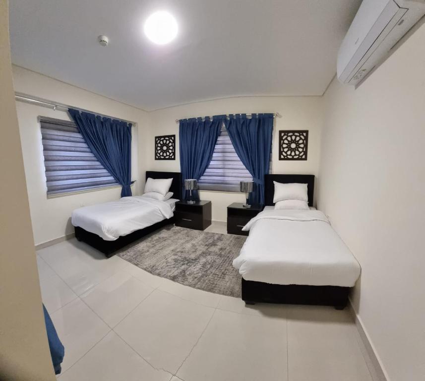 a bedroom with two beds and blue curtains at Byblos Prime in Aqaba