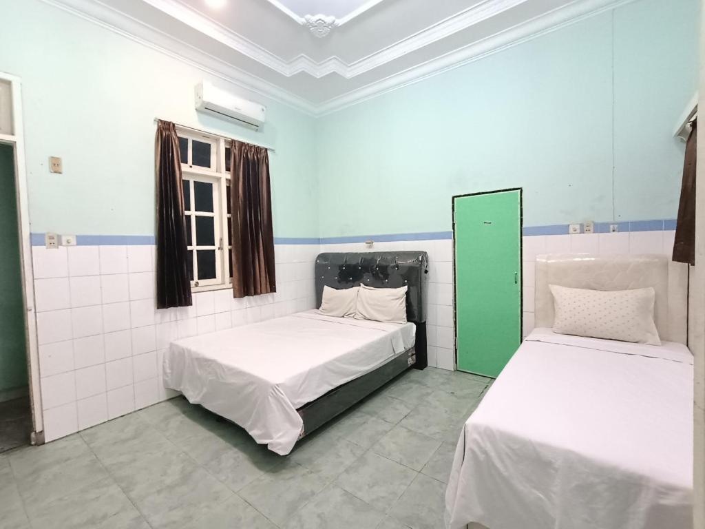 two beds in a room with blue and white walls at OYO 91874 Kisaran Residence Syariah in Kisaran