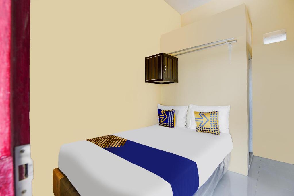 a bedroom with a bed with white and blue pillows at SPOT ON 91883 Kost 2 Putra Syariah in Sidoarjo