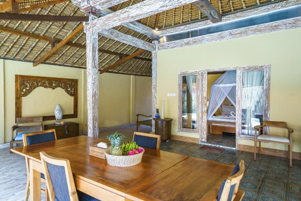 een eetkamer met een tafel en een kamer met een bed bij Villa Matahari - Cute 1 bdr villa with private pool in Gili Meno