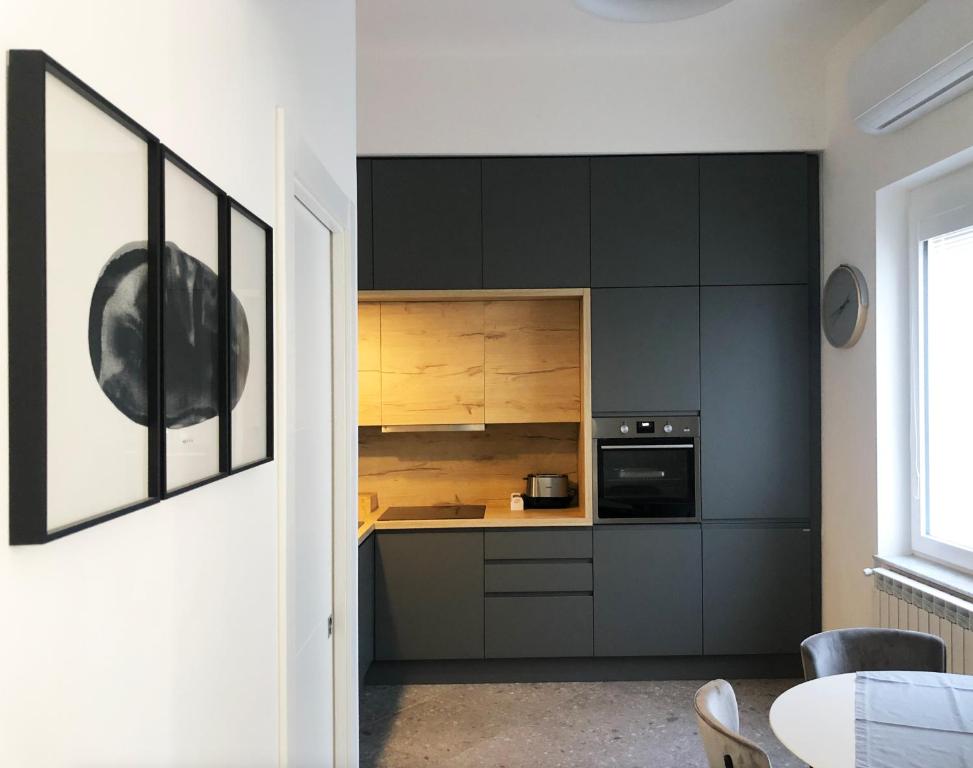 una cocina con armarios grises y un aparato negro en Lily Apartment Napoli en Nápoles