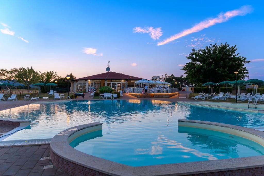 een groot zwembad met stoelen en parasols bij Casa in Maremma Tuscany Village in Scarlino