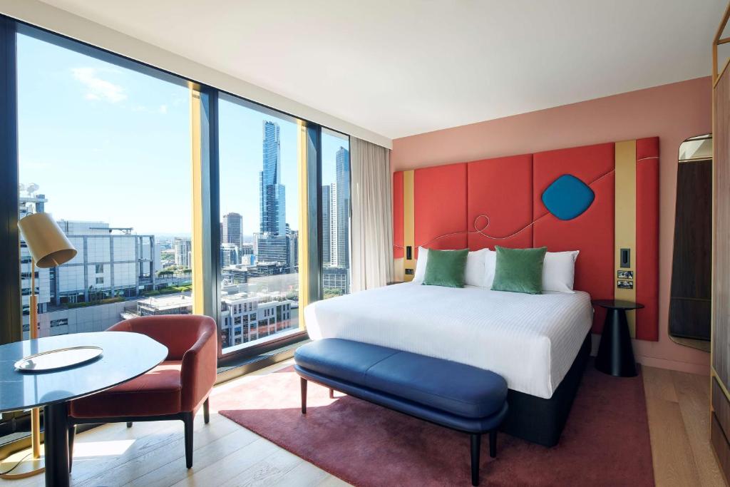 メルボルンにあるQuincy Hotel Melbourneの大きなベッド、テーブルと椅子が備わるホテルルームです。