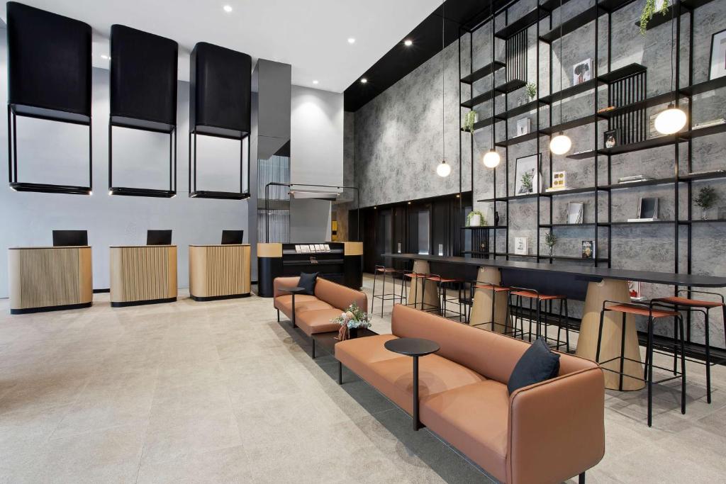 a lobby with couches and chairs and a bar at Travelodge Hotel Melbourne Docklands in Melbourne