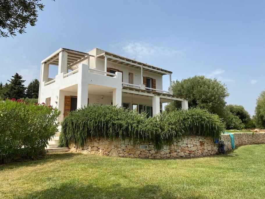 ein weißes Haus auf einer Steinmauer in der Unterkunft Villa Agosto, luxe villa met zwembad en zeezicht in Puglia in Carovigno