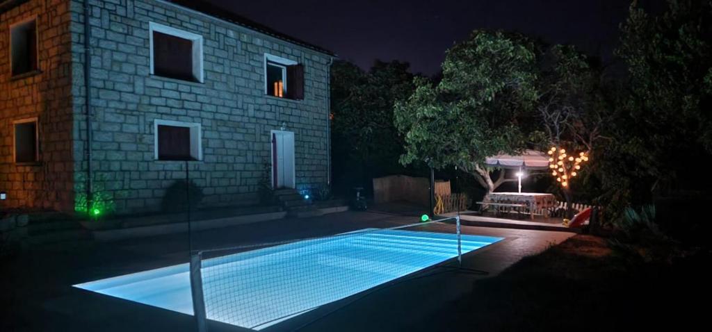 a swimming pool in front of a house at night at Bottega in Petreto-Bicchisano