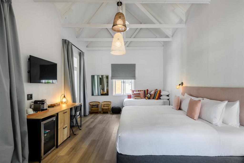 a bedroom with two beds and a desk and a tv at iGadi House Boutique Hotel in Cape Town