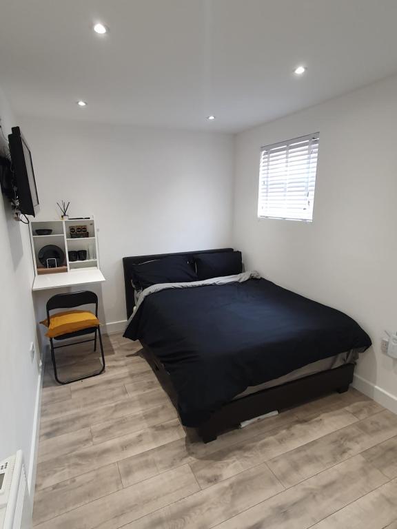 a bedroom with a black bed and a wooden floor at The Suite in Grays Thurrock