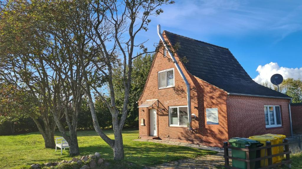 a small brick house in a field with trees at Ferienhaus Hoddebüll nah an der Nordsee in Emmelsbüll-Horsbüll