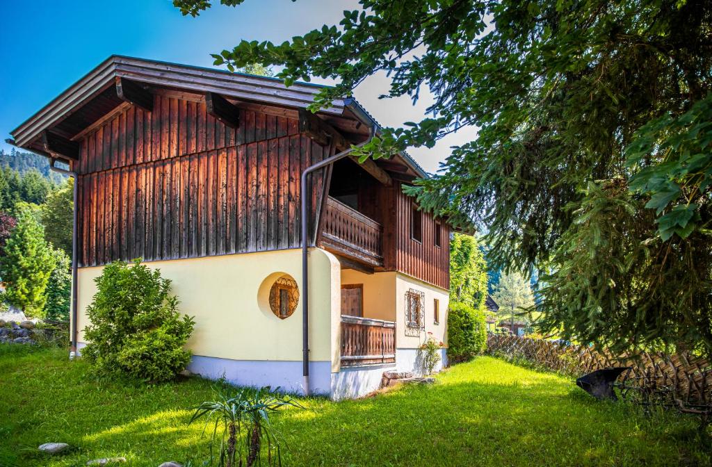 a house with a wooden roof and a green yard at Ferienhäuschen Millinghof in Leogang