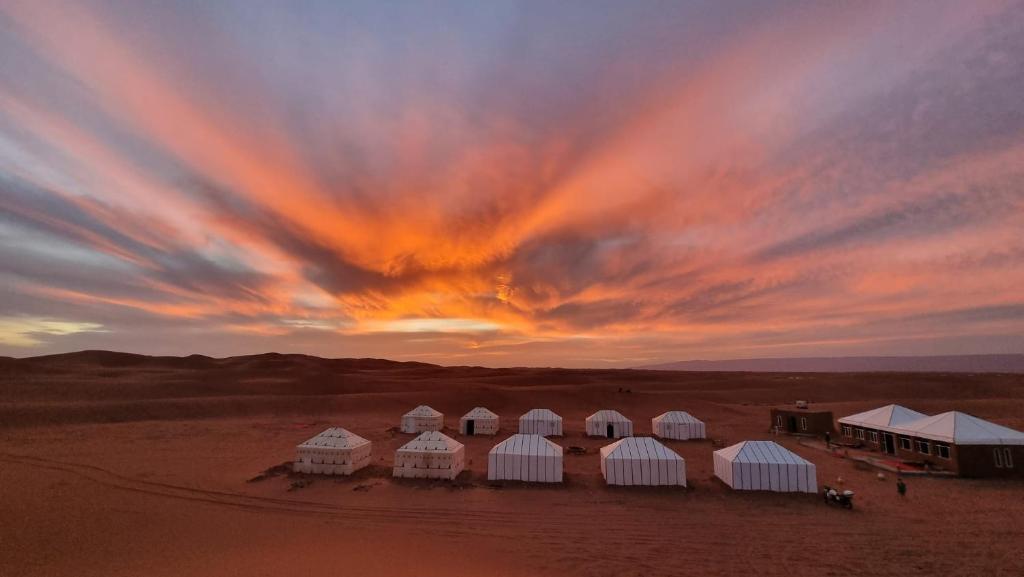 um grupo de tendas brancas no deserto ao pôr do sol em Sun Bivouac Chegaga em El Gouera