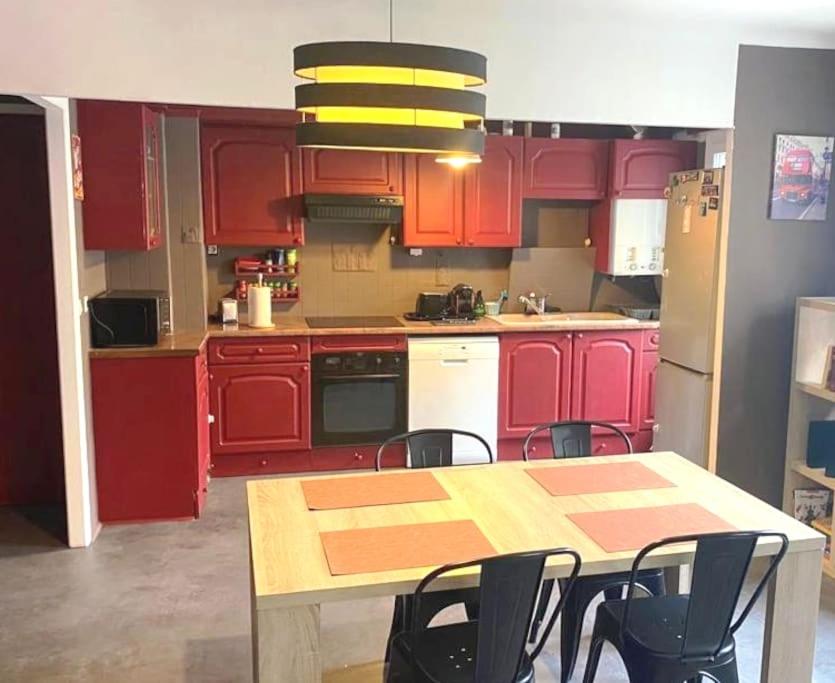 a kitchen with red cabinets and a table and chairs at Le Passe-Port pour Marseille in Marseille
