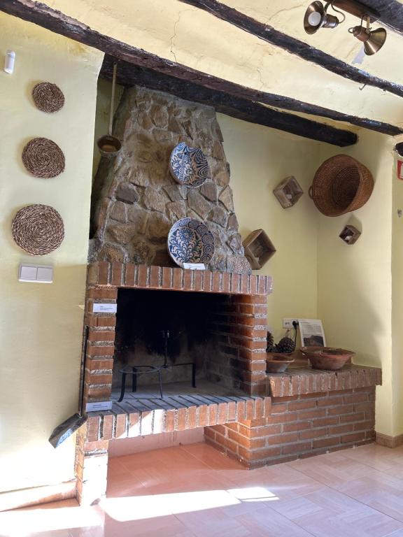 a brick fireplace with plates on the wall at Casa Rincón in Iznatoraf