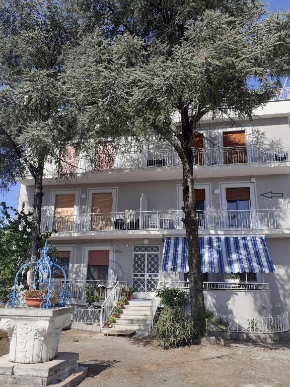 a white building with a tree in front of it at Luli Holidays Paestum in Paestum