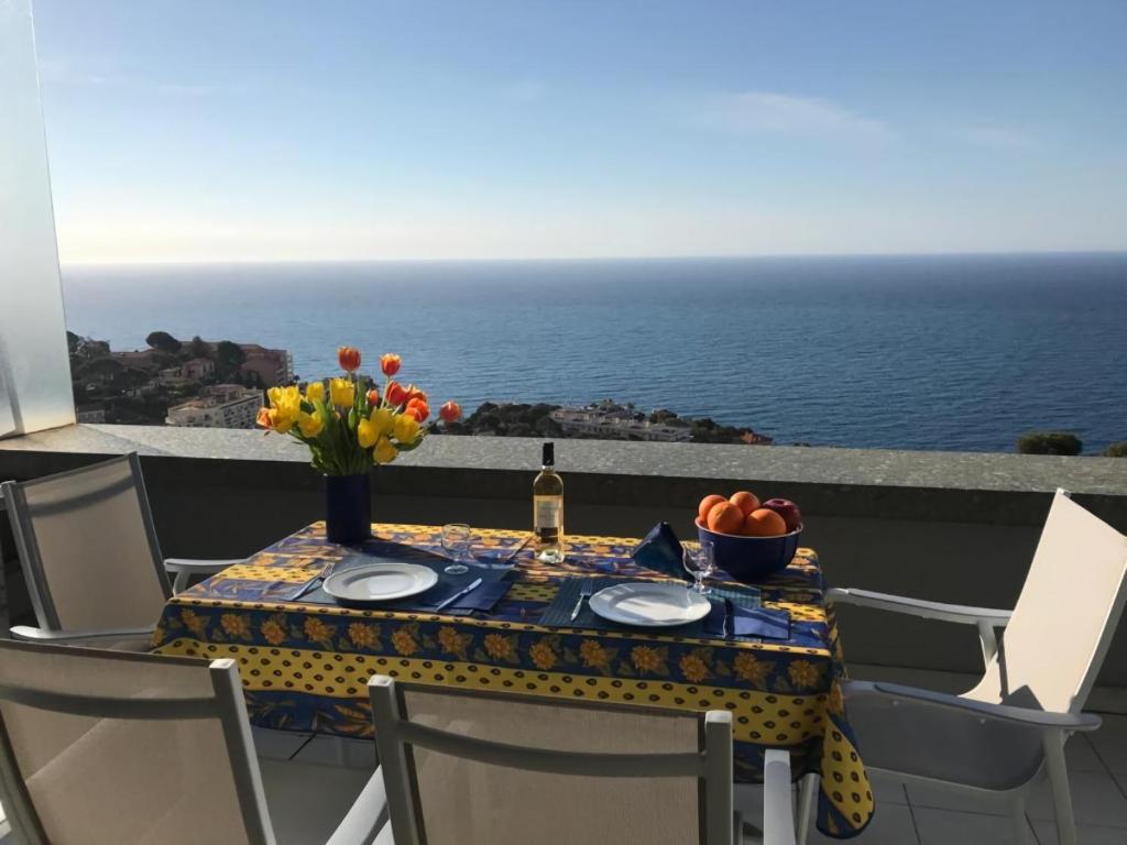 einen Tisch mit Blumen und eine Flasche Wein auf dem Balkon in der Unterkunft les étoiles between sea and stars in Cap d'Ail