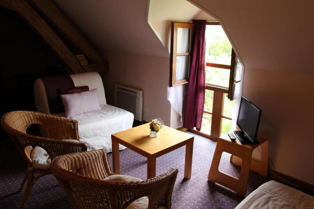 sala de estar con cama y mesa con sillas en Le Clos de Châtres, en Oisly