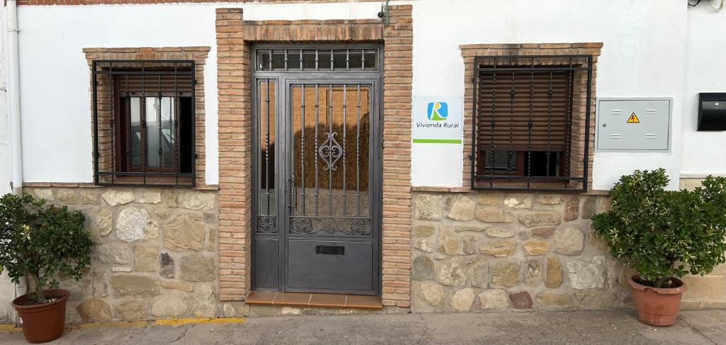 a brick building with a black door and two windows at Casa Enmedio in Iznatoraf