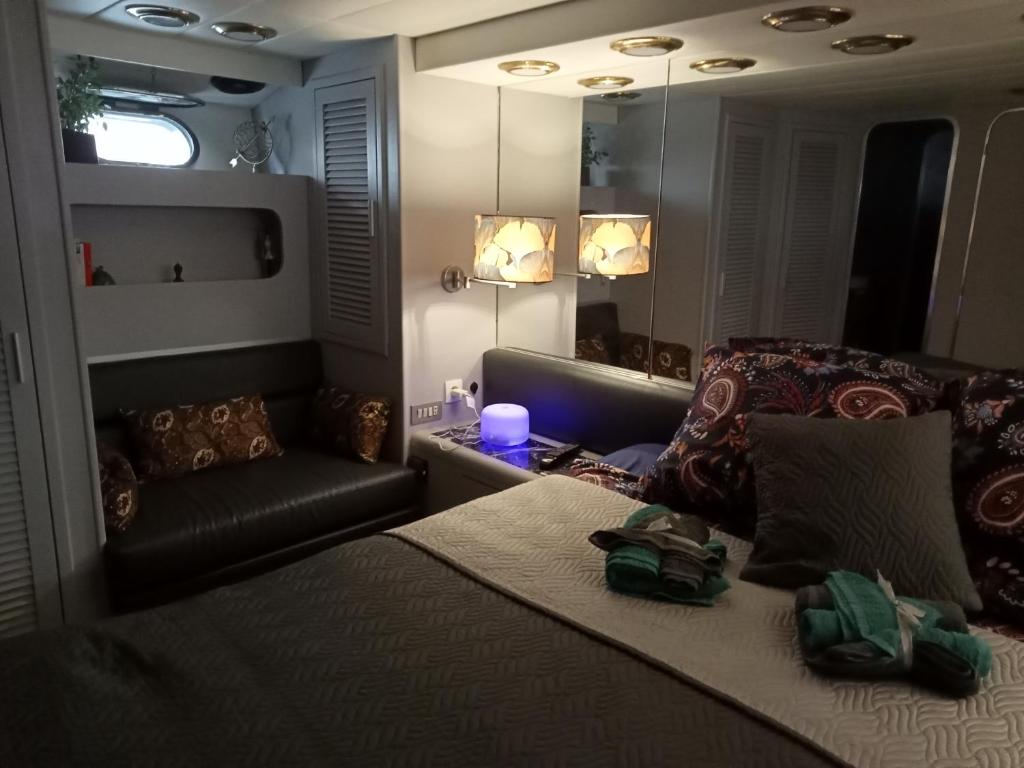 een slaapkamer met een bed, een bank en een spiegel bij Loc de cabines sur Yacht in Gruissan