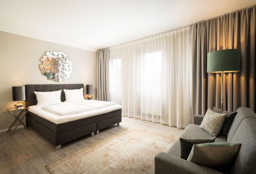 - une chambre avec un lit et un canapé dans l'établissement elaya hotel hannover city, à Hanovre