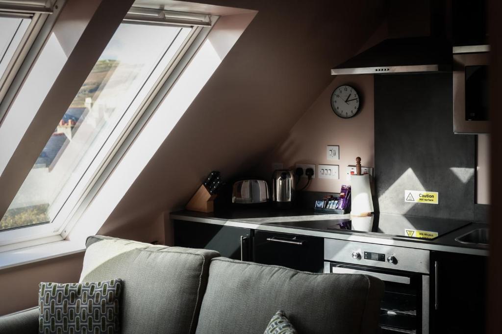 a kitchen with a couch and a stove and a clock at Nort Bode Apartments in Lerwick