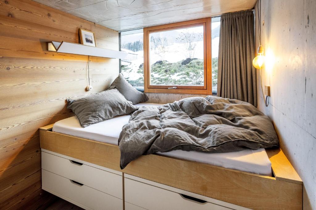 ein Bett in einem winzigen Haus mit Fenster in der Unterkunft Bleibe in Bad Kohlgrub