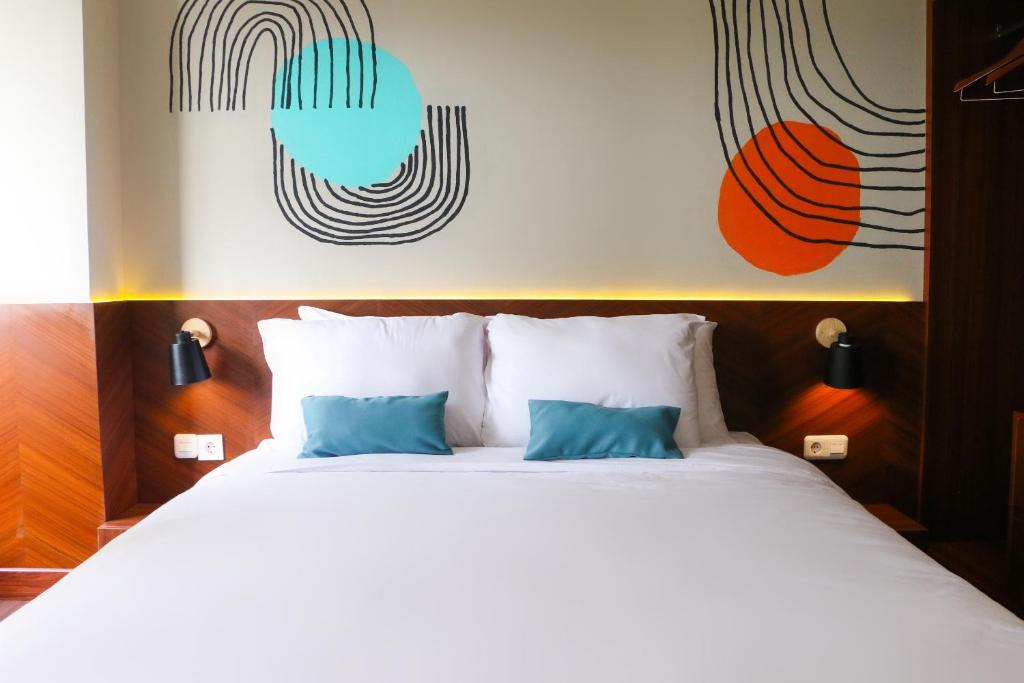 1 dormitorio con 1 cama blanca grande con almohadas azules en Stay G Service Residence Jatibening en Kaliastana