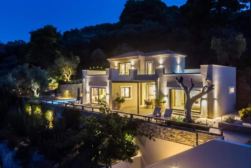une grande maison blanche avec une piscine la nuit dans l'établissement Villa Antigone Luxury Retreat, à Skopelos