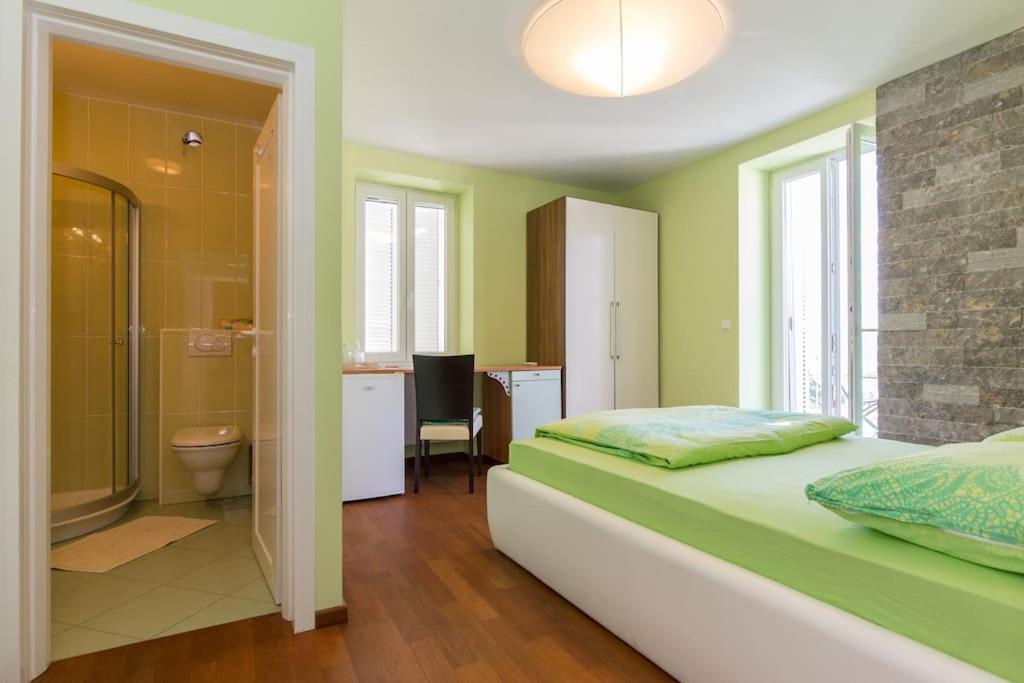 Villa Ajda - Green room في أوميشالي: غرفة نوم بسرير وحمام مع دش