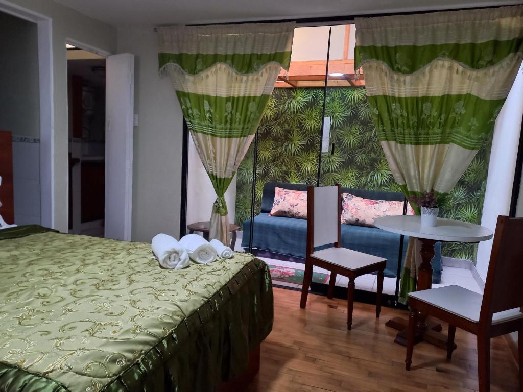 1 dormitorio con 1 cama, mesa y sillas en Miraflores Departamentos, en Lima