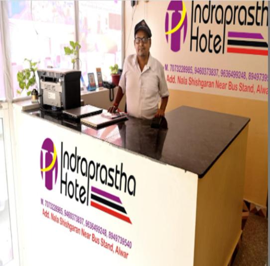 un hombre parado frente a una recepción en Hotel Indraprastha By WB Inn, en Alwar