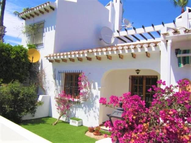 een wit huis met roze bloemen in de tuin bij Beautiful 2 Bedroom Bungalow with Communal Pools in Villamartin