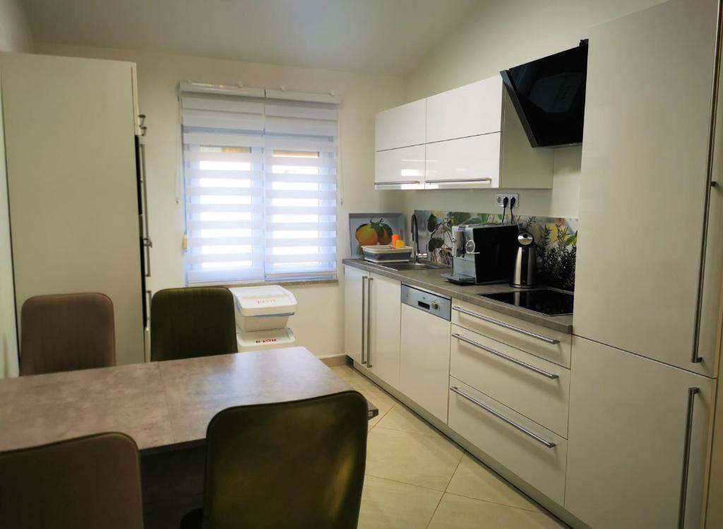 kuchnia z białymi szafkami, stołem i krzesłami w obiekcie Apartments Petar Pan w Fažanie