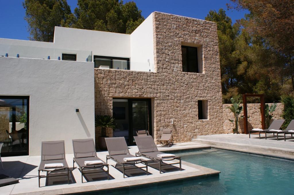 eine Gruppe von Stühlen neben einem Pool in der Unterkunft Extravagant Ibiza Villa Casa Tranquila SArgamassa 5 Bedrooms Fantastic Sea Views and Private Pool Santa Eulalia in Santa Eulària des Riu