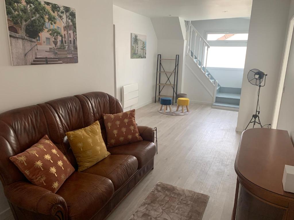 sala de estar con sofá de cuero marrón y escaleras en Villa Tenjin Chambre 17, en Bondy