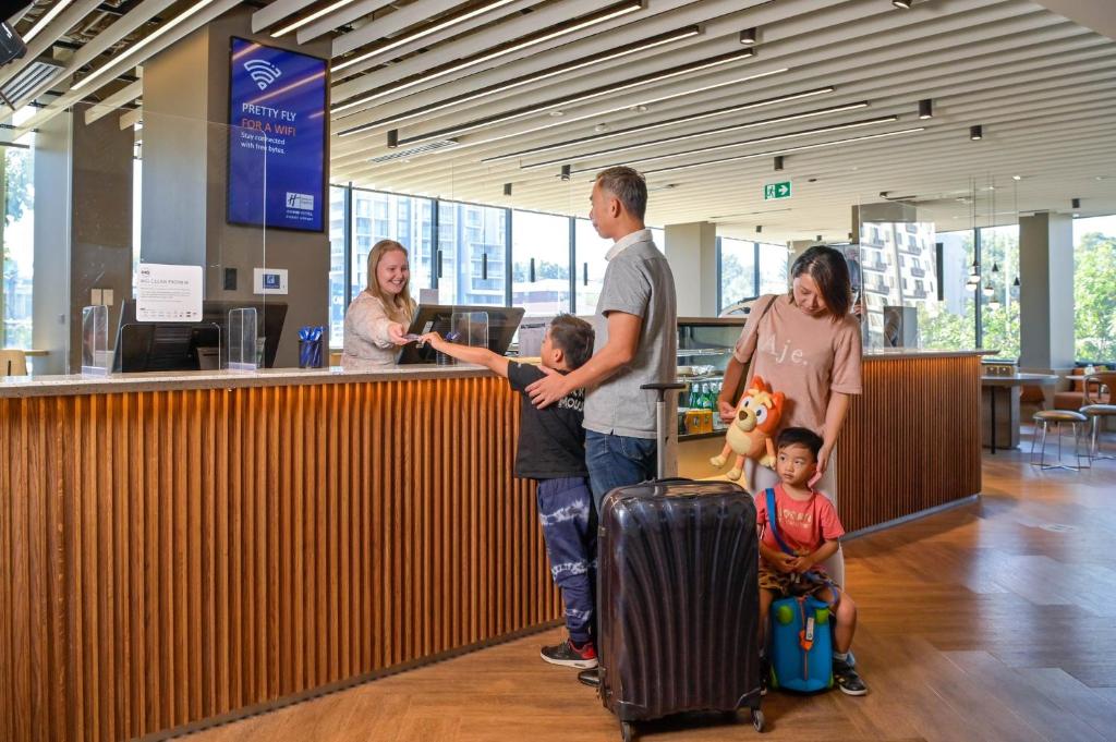 Holiday Inn Express Sydney Airport, an IHG Hotel في سيدني: مجموعة أشخاص واقفين في مطار مع الأمتعة