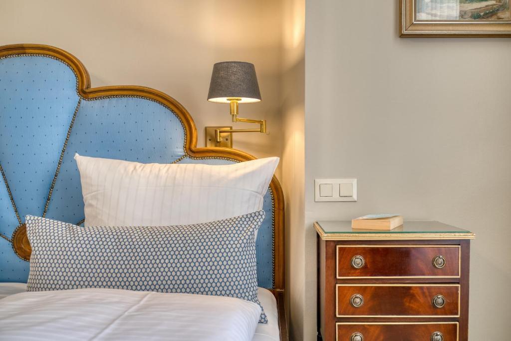 a bed with a blue headboard next to a night stand at Hotel Eisenhut in Rothenburg ob der Tauber