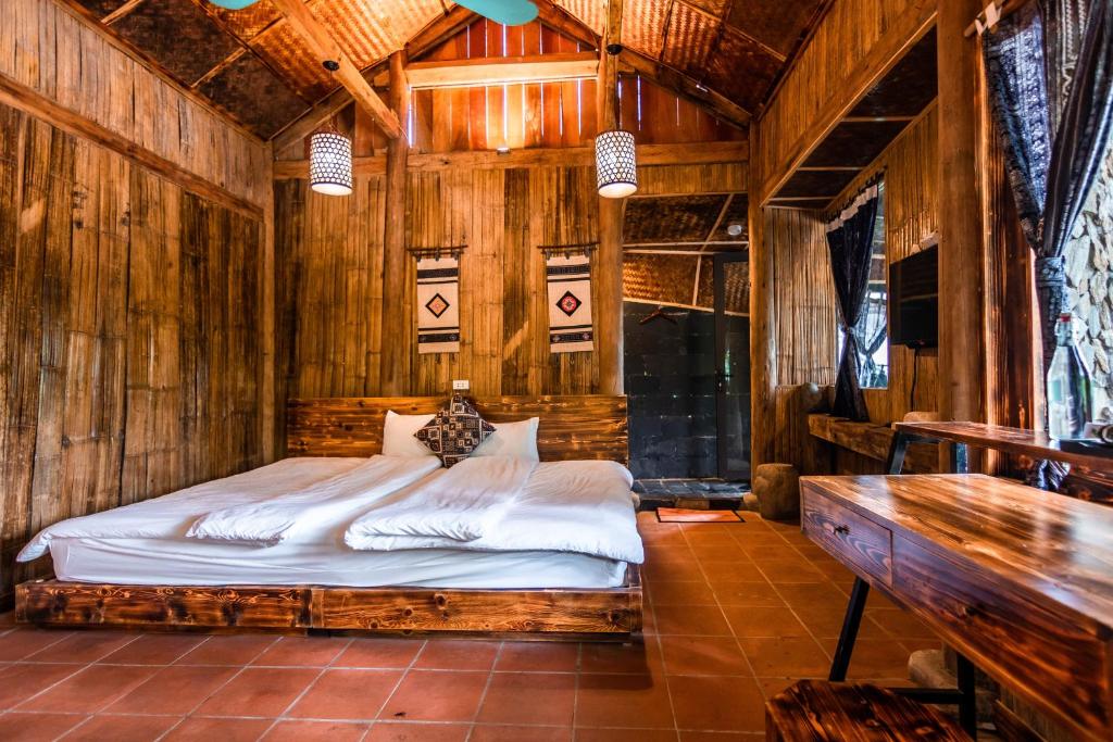 1 dormitorio con 1 cama en una pared de madera en Sapa Riverside Ecolodge & Spa, en Sa Pa