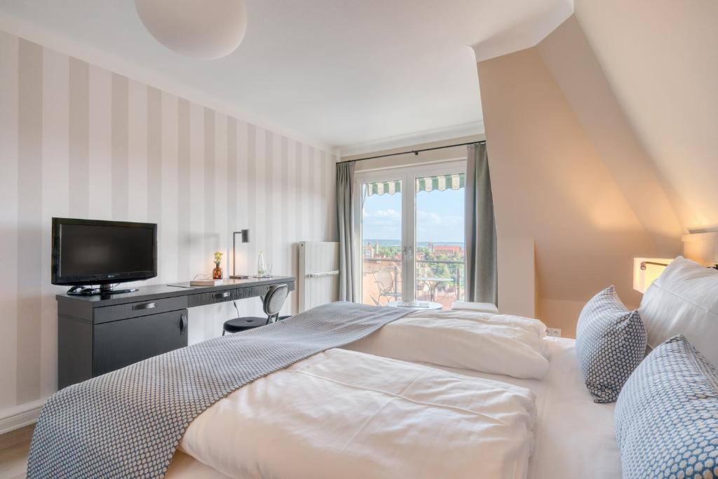 a bedroom with a bed with a television and a window at Hotel Eisenhut in Rothenburg ob der Tauber
