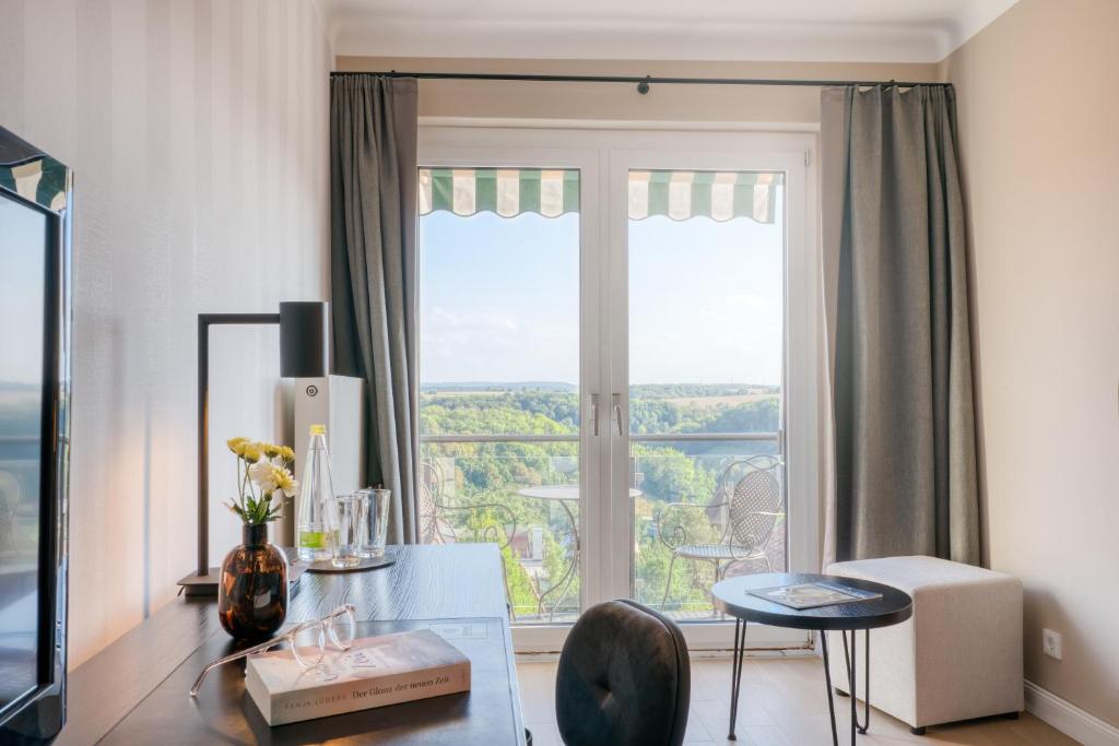 a living room with a table and a large window at Hotel Eisenhut in Rothenburg ob der Tauber
