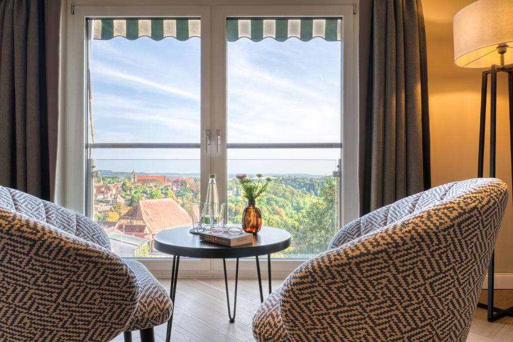 a room with two chairs and a table and a large window at Hotel Eisenhut in Rothenburg ob der Tauber