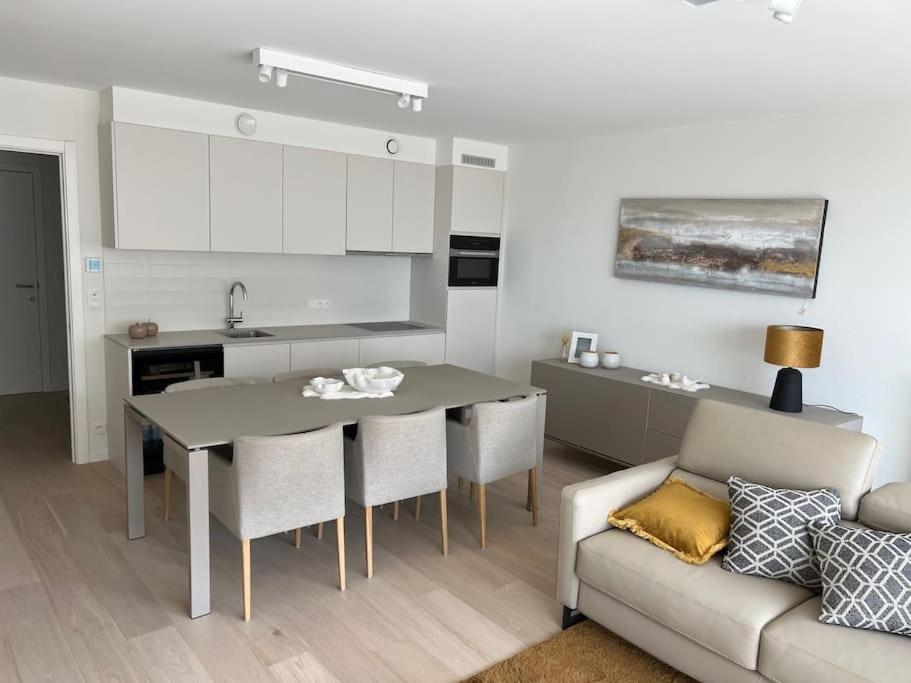 cocina y sala de estar con mesa y sofá en Oostende luxueus appartement 4p zeezicht & parking, en Ostende