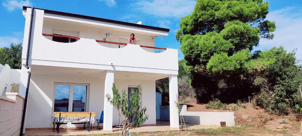 een wit huis met een tafel en een boom bij Casa Nonno Remo in Porto Pino