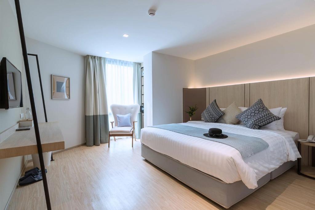 ein Hotelzimmer mit einem großen Bett und einem Stuhl in der Unterkunft Bella B Hotel in Nonthaburi