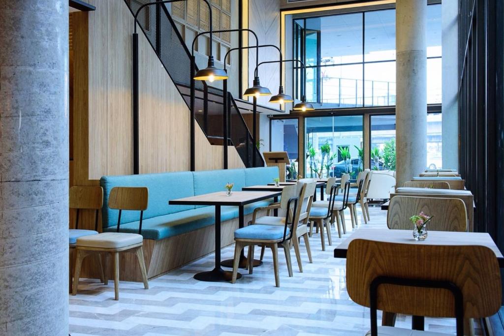 un restaurante con mesas, sillas y ventanas en Bella B Hotel, en Nonthaburi