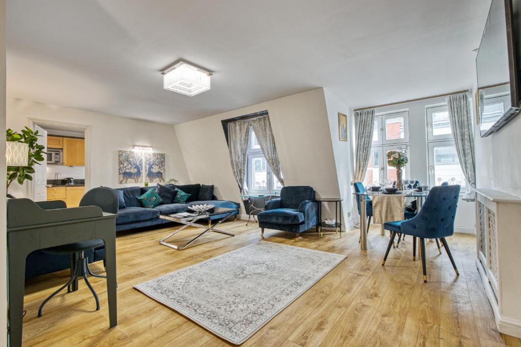 sala de estar con sofá azul y sillas en 2-Bed 2-Bathroom Mayfair - Maddox St en Londres