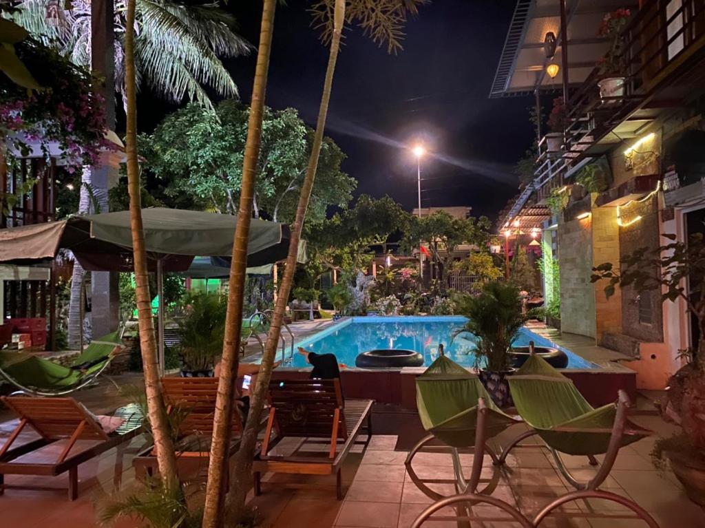 - une piscine de nuit avec des chaises et une table dans l'établissement Phong Nha Tuan Garden House, à Phong Nha