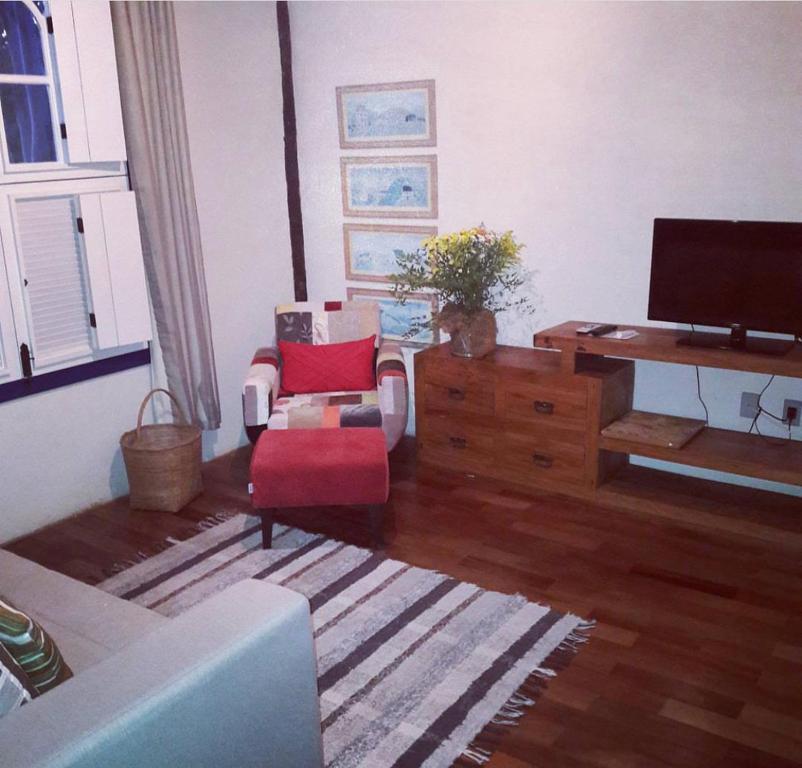 uma sala de estar com um sofá e uma televisão em Pousada Flor de Íris em São João del Rei