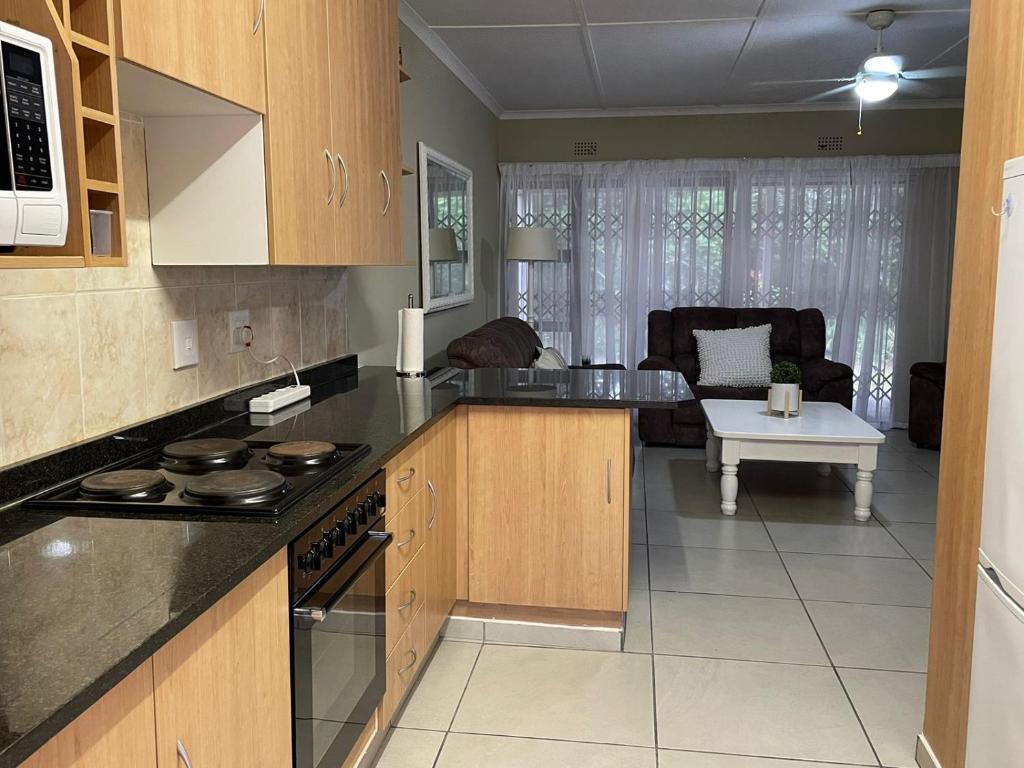 a kitchen with wooden cabinets and a living room at Sea Casa in Scottburgh