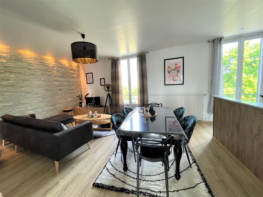 een woonkamer met een tafel en een bank bij Le Neufchâtel appartement cosy 3 chambres in Reims