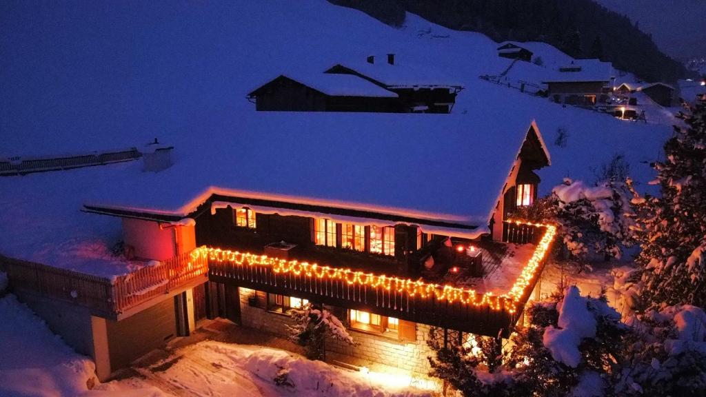 uma casa coberta de luzes de Natal na neve em Chalet Alten em Klosters Dorf